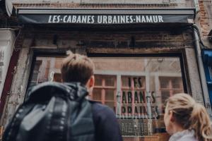 那慕尔Les 3 Cabanes Urbaines - centre historique的男人和女人在商店的窗口里看