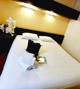 里摩日Hôtel du Parc Limoges & Restaurant "Le temps d'une pause"的一张带两个枕头的白色床和一本书