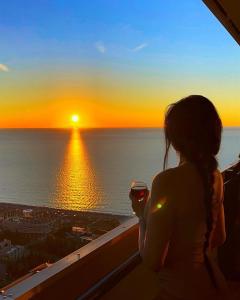 巴统Panorama Sea View Central City Batumi & ApartHOTEL的站在阳台上欣赏日落的女人