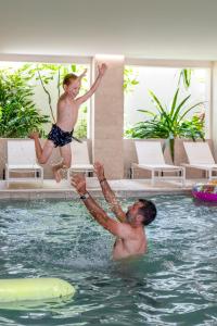 锡富尔勒普拉日Hôtel Helios & SPA - Ile des Embiez的跳入游泳池的男人和男孩