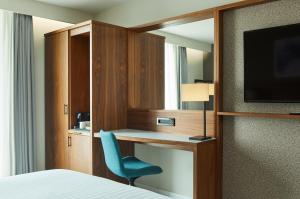霍利伦敦盖特威克机场万怡酒店的一间卧室配有书桌、椅子和电视。