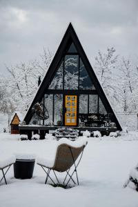 波卢巴库苏斯Porumbacu Garden的房屋前有两把椅子,被雪覆盖