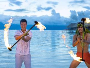 MaharepaSofitel Kia Ora Moorea Beach Resort的一名男子和女子用火棍站在海滩上