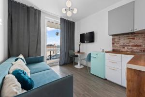 华沙RentPlanet - Apartamenty Wiktoryn的一间带蓝色沙发的客厅和一间厨房