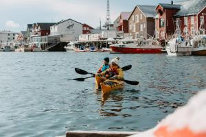亨宁斯韦尔Henningsvær Bryggehotell - by Classic Norway Hotels的两个人划皮艇在港口附近的水里