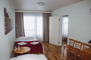哈普萨卢Hotel Promenaadi的酒店客房带两张床和一张桌子以及椅子。