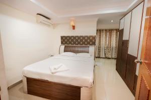 班加罗尔Falcon Suites Koramangala的一间小卧室,配有白色床单