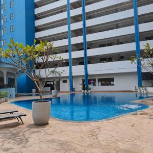 Mutiara Melaka Beach Resort by Ally的一座大建筑,设有一座带盆栽树的游泳池