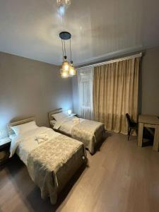 祖格迪迪Hotel Lumi的一间卧室配有两张床、一张桌子和一个吊灯。