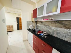 印多尔Home Escape 1BHK Apartment Near Bombay Hospital的厨房配有红色橱柜和黑色台面