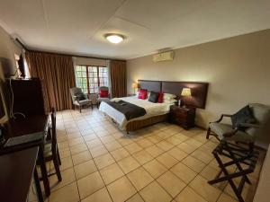 比勒陀利亚Edelweiss Corporate Guest House的配有一张床和一把椅子的酒店客房