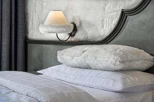 摩德纳迪-坎皮格里奥希尔米塔吉毕欧酒店的一张带白色枕头和灯的床