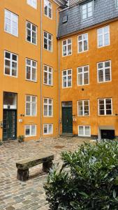 哥本哈根ApartmentInCopenhagen Apartment 1580的一座橙色的建筑,前面有长凳