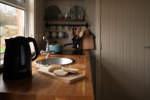 奥马Shepherds Hut near Gortin Omagh的厨房柜台配有咖啡壶和切盘上的饼干