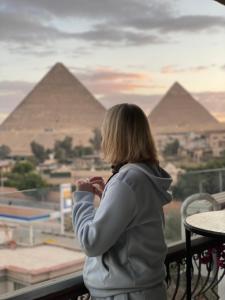 开罗Unique Pyramids View INN的一位从阳台上望向金字塔的女人