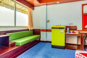 素叻OYO 441 Grand Thara Hotel的客房设有绿色沙发和冰箱。