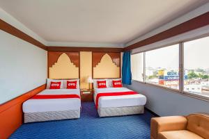 素叻OYO 441 Grand Thara Hotel的酒店客房,设有两张床和一张沙发