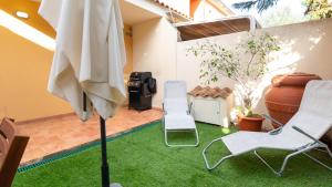 ElmasWelcomely - Villino Octagon的庭院设有草坪、两把椅子和一把遮阳伞