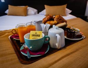 凯恩Hotel Astrid Caen centre的床上的早餐食品和饮料托盘