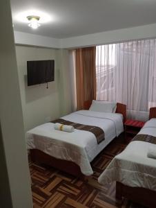 库斯科Posada de Mama的酒店客房设有两张床和一台平面电视。