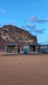 瓦迪拉姆WADi RUM NOOR CAMP的沙漠中的两座建筑,背景是一座山