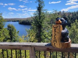 Algonquin HighlandsThe Bear Cave Cottage at Little Kennisis Lake的举着读新工作标志的熊的雕像