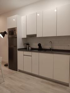 马德里Gregorio Marañón Apartment 3的厨房配有白色橱柜和不锈钢冰箱