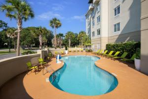 查尔斯顿SpringHill Suites by Marriott Charleston Riverview的一座带椅子的酒店游泳池以及一座建筑