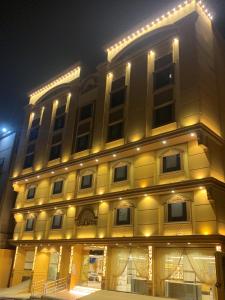 麦加فندق انوار المشاعرالفندقية的一座黄色的大建筑,晚上有灯
