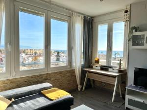 马拉加Espectacular apartamento junto al mar, con piscina en Málaga的客厅设有窗户和桌子及书桌