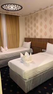 麦加فندق انوار المشاعرالفندقية的一间设有两张白色鲜花的床的房间