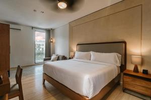 梅里达Kahal Boutique Hotel的卧室设有一张白色大床和一扇窗户。