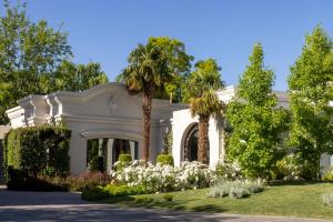 卢汉德库约Susana Balbo Winemaker´s House的棕榈树和鲜花的白色房子