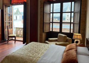 昆卡Floré Hotel Boutique Cuenca的一间卧室配有一张床、一把椅子和窗户。