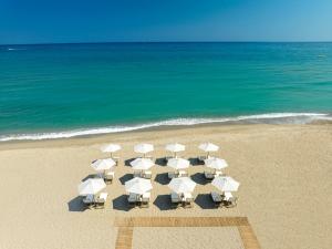 罗希姆诺Calla Luxury Seafront Suites的海滩上的一组椅子和遮阳伞