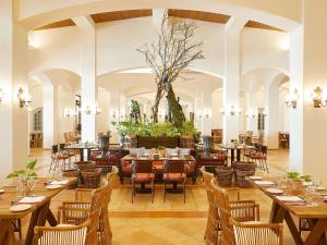 卢特拉基利尼斯Grecotel Olympia Oasis & Aqua Park的一间设有木桌和椅子的餐厅