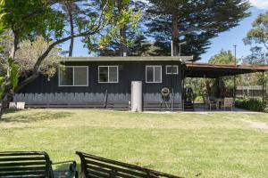 SomersShoreline Sanctuary - A Retro Family Beach Shack的一间黑色的小房子,在院子里设有野餐长凳