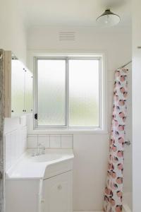 SomersShoreline Sanctuary - A Retro Family Beach Shack的白色的浴室设有水槽和窗户。