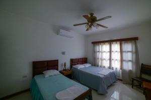 里瓦斯HOSTAL RIVAS INNS的一间卧室配有两张床和吊扇