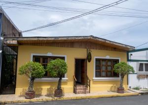 里瓦斯HOSTAL RIVAS INNS的前面有两棵树的黄色房子