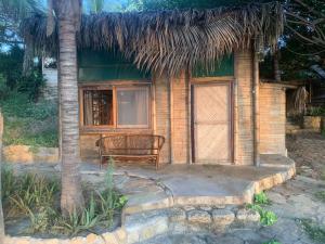 维加伊托La Cabaña del Mar Vichayito的一个带长凳和稻草屋顶的小房子