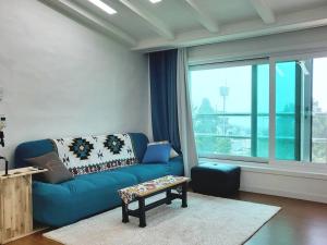 济州市Aewol Gwangryeong House的客厅设有蓝色的沙发和大窗户