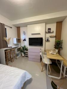 宿务Kristinas Homestay- Cozy Resort Vibe Condotel的一间卧室配有一张床、一张书桌和一台电视