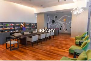 吉隆坡Regalia Exclusive Hostel的一间图书馆,里面摆放着椅子和桌子