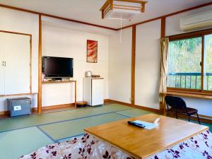 Kanayamaおんせん民宿望海的客厅配有桌子和电视