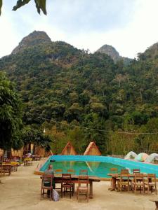 Ban NongkhamNongKhiaw CampingSite Swimming Pool的坐在游泳池前桌边的人