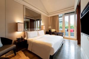 新加坡The Capitol Kempinski Hotel Singapore的卧室配有一张白色的大床和一张沙发。