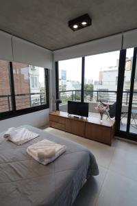 布宜诺斯艾利斯OWN Belgrano Studios & Suites的卧室配有一张床、一张书桌和窗户。