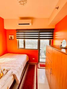 马尼拉Happy Hideout @ Grass Residences的一间卧室拥有橙色的墙壁、一张床和窗户