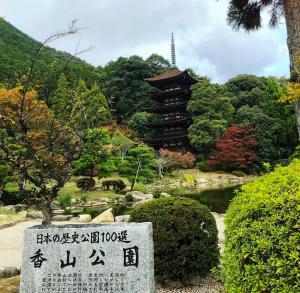 HikariKAMENOI HOTEL Setouchi Hikari的一座带宝塔的花园前方的石牌